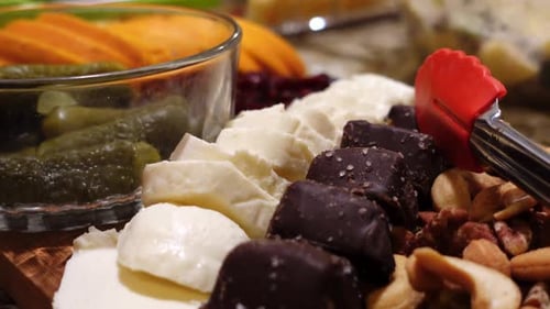 Un gros plan animé d'un plateau de charcuterie avec des cornichons, des tranches de mozzarella, des bouchées salées, un