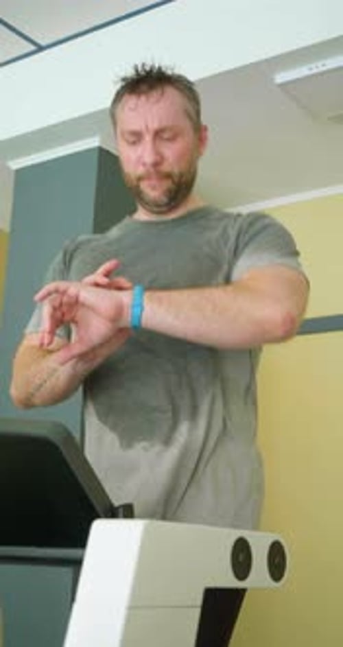Mann mittleren Alters schaut auf seine Smartwatch und passt den Trainingsprozess an