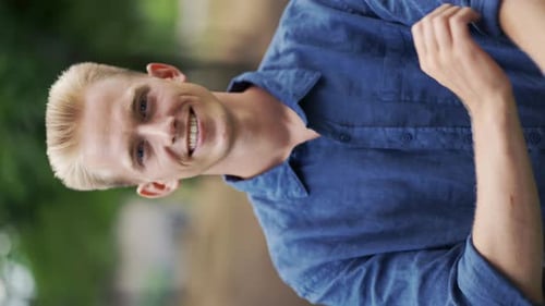 Closeup Portrait of a Young Happy Blond Man Standing in Nature Between Trees in the Park Relaxing