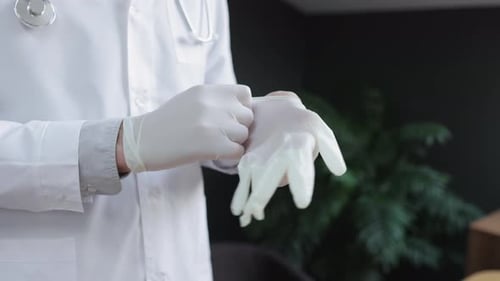 Male Doctor Putting on Gloves and Standing in Interior of Clinic During Working Day Spbi