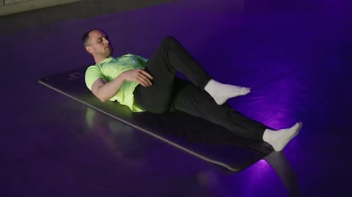 Man Lying on Mat Doing Knee to Chest Exercise
