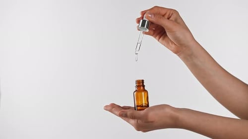 Woman adding liquid drops to small brown bottle