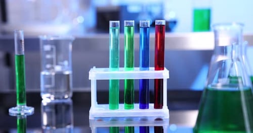 Scientist putting test tube with orange liquid into stand at table in laboratory, closeup