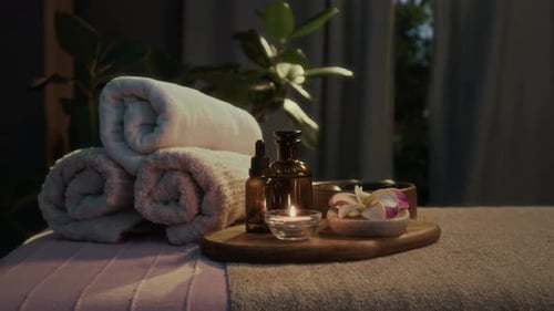 Close-up of Tray with Oil Bottles, Lit Candle, and Plumeria Flower in Spa Salon