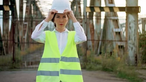 Woman Engineer in Uniform Put on Helmet Before Hard Work Near Metal Bridge Construction