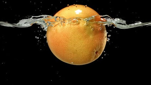 Grapefruit Sinking in Water with Splashes on Black