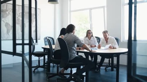 Young business people in formal clothes sitting by the table and working in the office with document