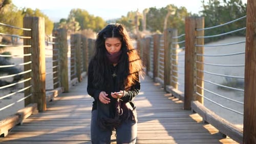 Thoughtful Woman on Wooden Bridge with Mobile Phone
