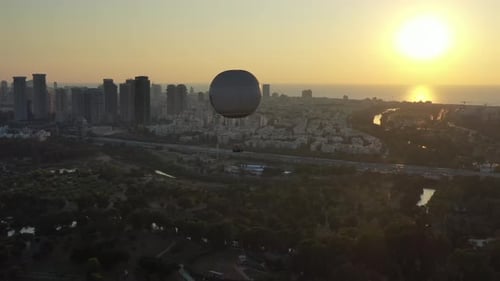 Aerial Shot Of Hot Air Balloon Descending Over Yarkon Park Against Sky In City