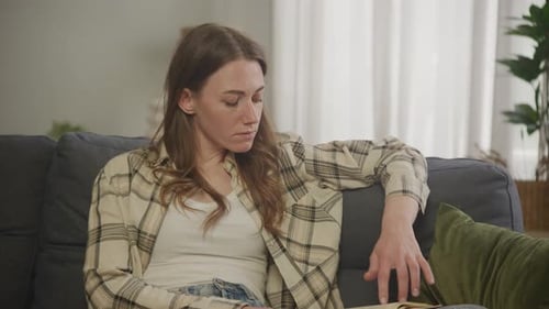 Young Woman Reading a Book on Couch