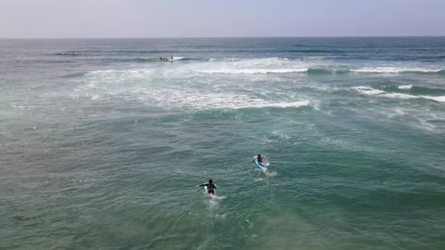 Drone Shot Of Two Young Surfers Paddling Out Into the Pacific Ocean