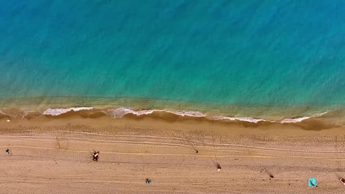 Sandy beach with waves slowly splashing by. Beautiful relaxing view of the shore from top