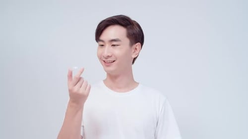 Young smiling man holding invisalign braces over white background studio