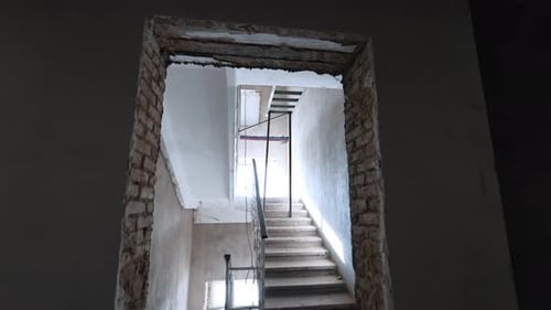 Entering the hall with stairs and grey walls in the unfinished building. Construction concept.