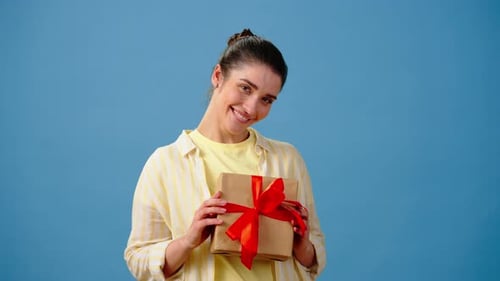 Happy Woman Holds a Gift and Points