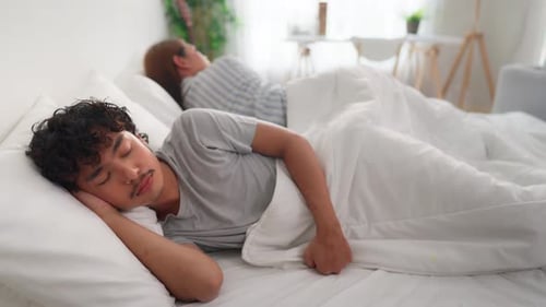 Asiatisches LGBTQ-Paar liegt mit schmerzhaftem Streit nach dem Kampf auf dem Bett.