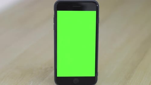 Isolated smartphone with green screen on a wooden table