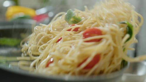 Tossing Hot Pasta with Veggies in Frying Pan