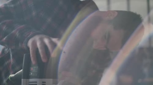 Carpenter sawing wood in moody workshop