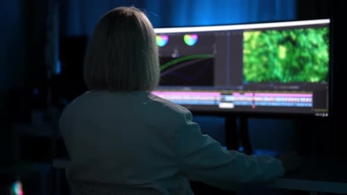 Tracking Shot From Back of Unrecognizable Experienced Female Video Maker Doing Color Grading in