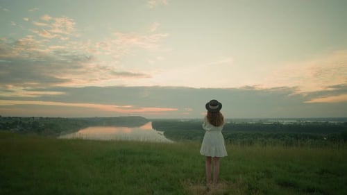 Thoughtful Woman in White Dress Gazing Over Lake at Sunset