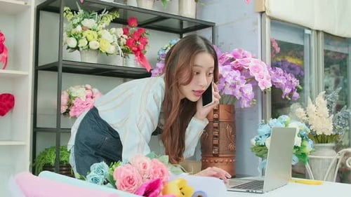 One young Asian female florist owner working in colorful flower shop store.