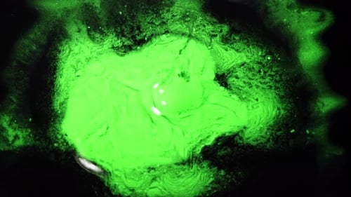Des liquides verts tourbillonnants se mélangent dans une photo d'une expérience scientifique au look surréaliste
