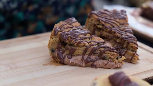 Primer plano de una rebanada de tarta rellena de mousse levantando a mano con guantes y rociando sobre una tabla de madera