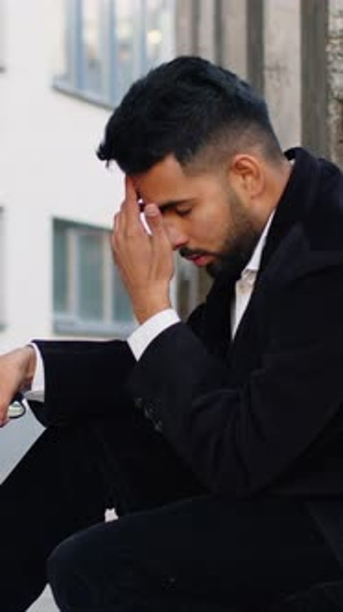 Thoughtful Man Leans Against Wall in Stylish Black Suit