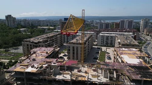 Sitio de construcción urbana con trabajadores y una gran grúa amarilla ensamblando un nuevo edificio residencial