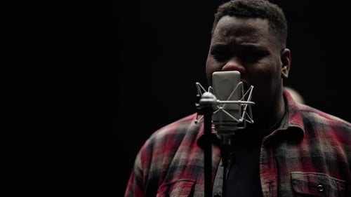 Man Singing Into Microphone in Recording Studio