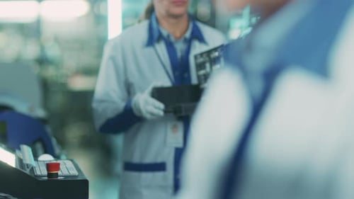 In einer High-Tech-Fabrik trägt eine Arbeiterin eine Charge mit einer zusammengebauten Elektronisch Leiterplatte