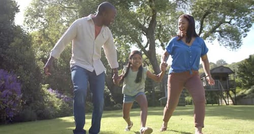 Playing in park, parents swinging children by their arms, enjoying family time