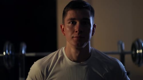 Front View Portrait of Satisfied Young Sportsman Standing in Darkness Looking at Camera Closeup