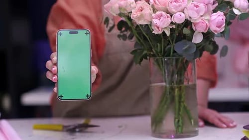 Bouquet of Flowers and Florist Hand Holding Smartphone with Green Screen Mock Up for Flower Delivery