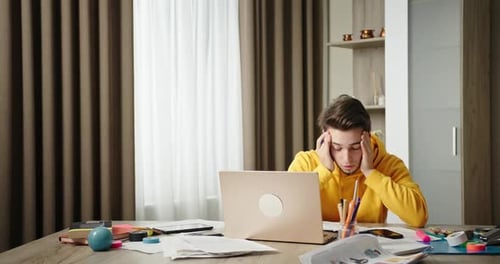 Young Guy Working at Home Home Office Sitting at a Desk Working on a Laptop Freelancer Tired From