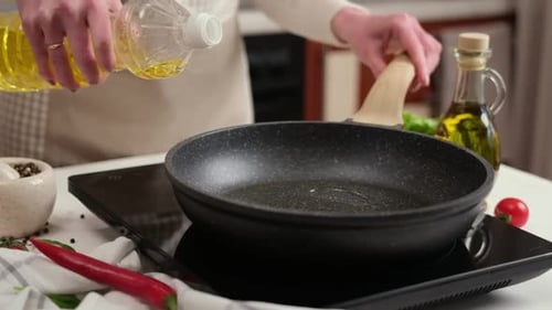 A Woman Pours Vegetable Oil Into a Frying Pan on the Induction Stove