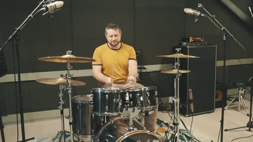 Professional Male Musician Playing Drum Kit in Recording Studio