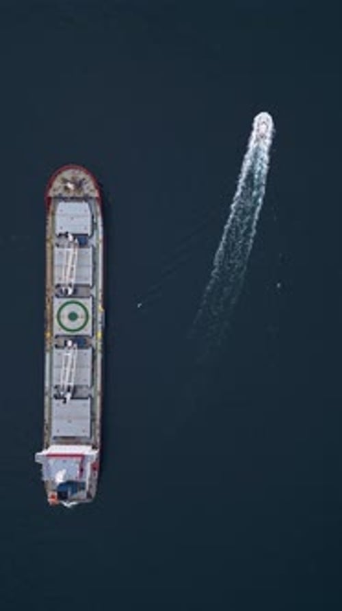 Grand cargo à proue rouge en pleine mer accompagné d'un remorqueur sous un ciel couvert Maritime