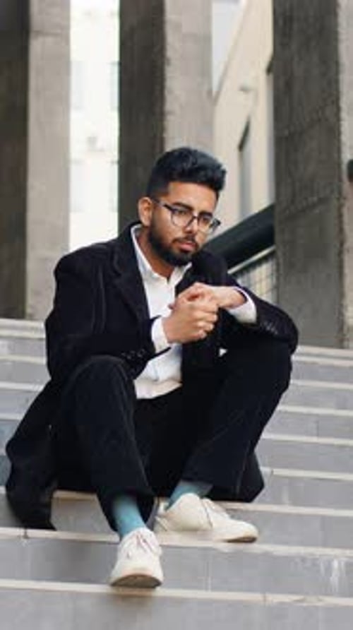 Thoughtful Young Man Sits on Steps Outdoors