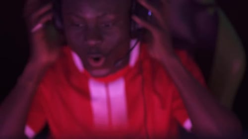 Focused Young Adult Playing Video Game with Headset