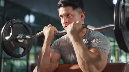 Caucasian sportsman slowly lift up weight machine barbell in stadium.