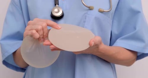 Doctor Holding Silicone Breast Implants in Hospital