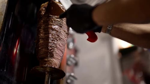 Cooking National Turkish Street Food Shawarma Cook Cut Meat on Spit By Large Knife Closeup View