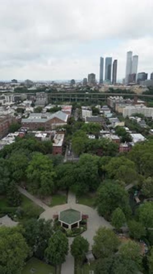 Reverse drone shot revealing Jersey City park expanding into skyline views, blending green space