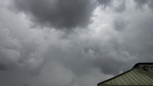 Zeitraffer von sich schnell bewegenden städtischen Sturmwolken, die über städtischen Dächern vorbeiziehen und Regen fällt