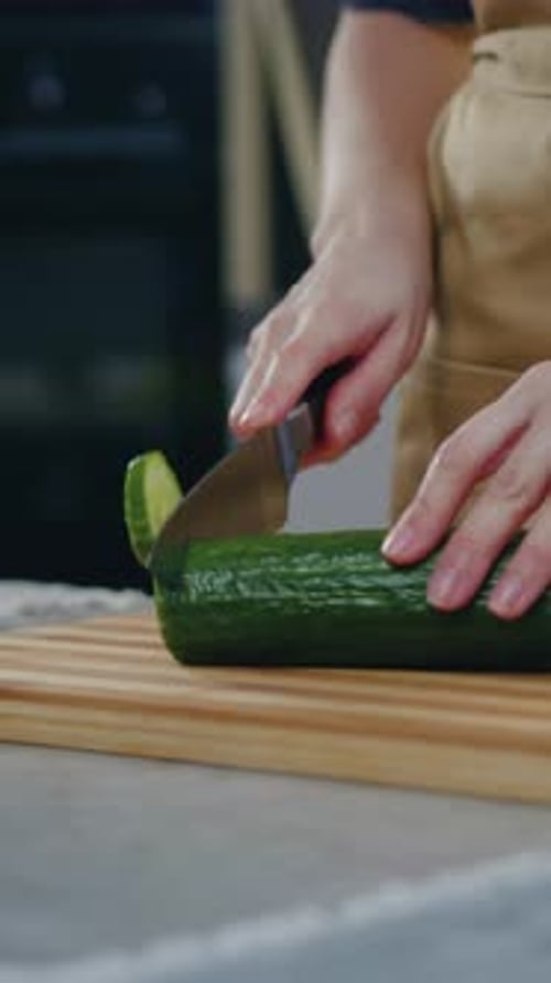 Close Up Woman Cutting Fresh Cucumber on Cutting Board While Preparing Vegetable Salad Standing Near