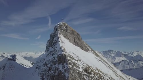 Flying towards and around a snow covered mountain peak with cross on it