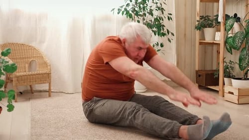 Senior Man Stretching Seated on Floor at Home