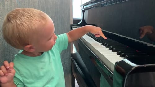 Blonde Toddler Playing Piano Indoors During Daytime